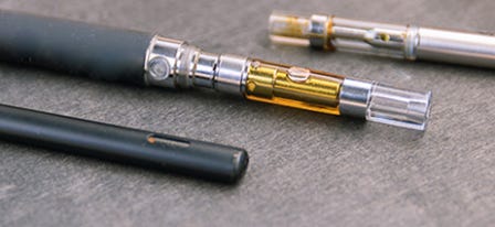 Three cannabis vapes laying on a table
