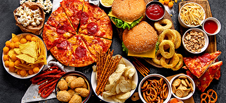 Large table filled with snack foods like pizza, burgers, pretzels, etc.