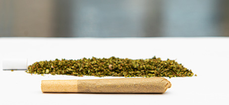 A joint on a table next to ground flower and a crutch