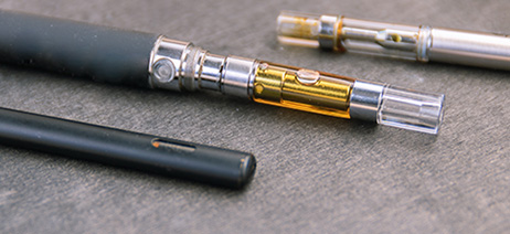 Three cannabis vapes laying on a table