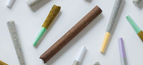 Cannabis joints and blunts in various shapes and sizes scattered across a white background