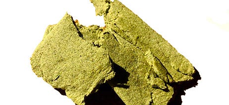 Brick of green bubble hash on a white background