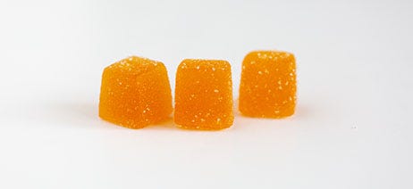 Three orange CBD gummies on a white background