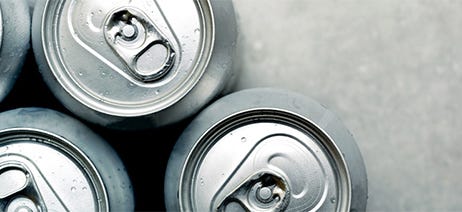 Four beverage cans sitting on a grey table