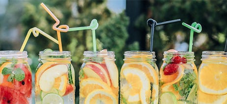 Six cannabis mocktails in mason jar glasses sitting on a table outside