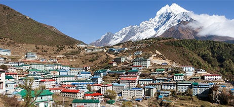 Colorful mountain homes in the Himalayan mountains in front of snow-capped mountains