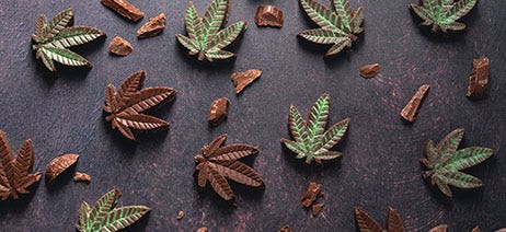 Chocolates in the shape of cannabis leaves on a black table