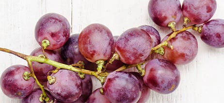 Bunch of purple grapes sitting on a white table