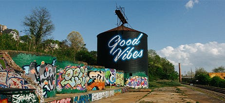 Grain silo with graffiti on it that says Good Vibes