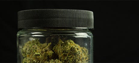 Clear jar with a black top and cannabis flower nuggets inside