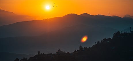 Shadowy mountains with a sun setting behind them