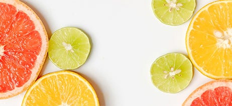 Lemons, limes, and grapefruits cut in half sitting on a white background