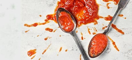 ketchup splattered on a table and across two spoons