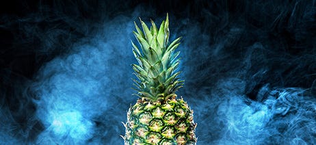 Large pineapple on a black background with smoke swirling around it