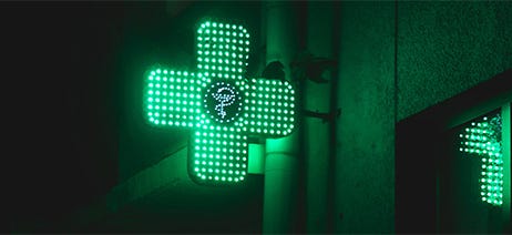 Pharmacy sign glowing in green lights at nighttime
