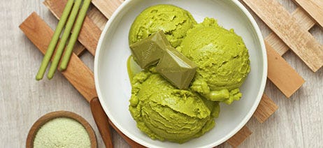 Green sherbet in a white bowl, on a wood trivet