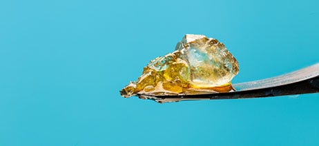 THC diamond on a dab tool in front of a blue background