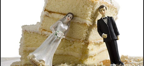 Slice of wedding cake with bride and groom figurines leaning against it