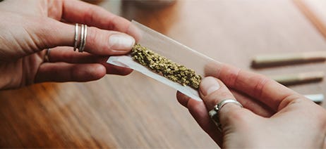 Two hands rolling popcorn flower into a pre-roll