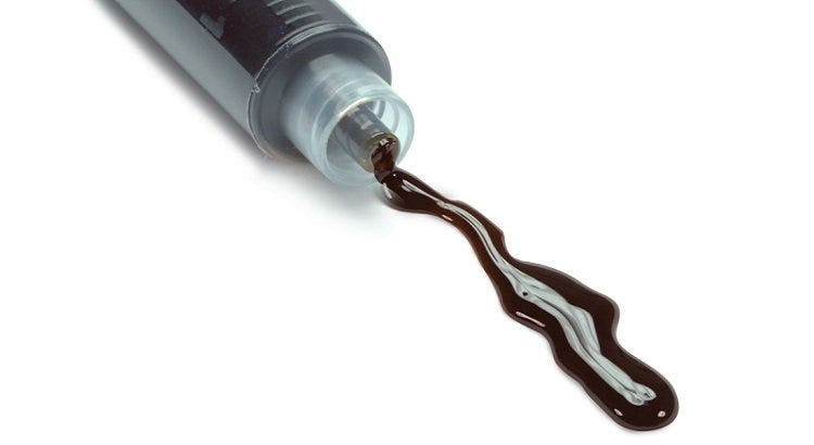 Black RSO being dispensed from a clear syringe
