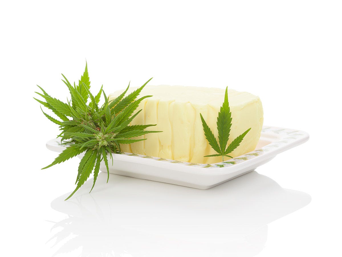 Cannabis butter on a white dish with cannabis leaves next to it
