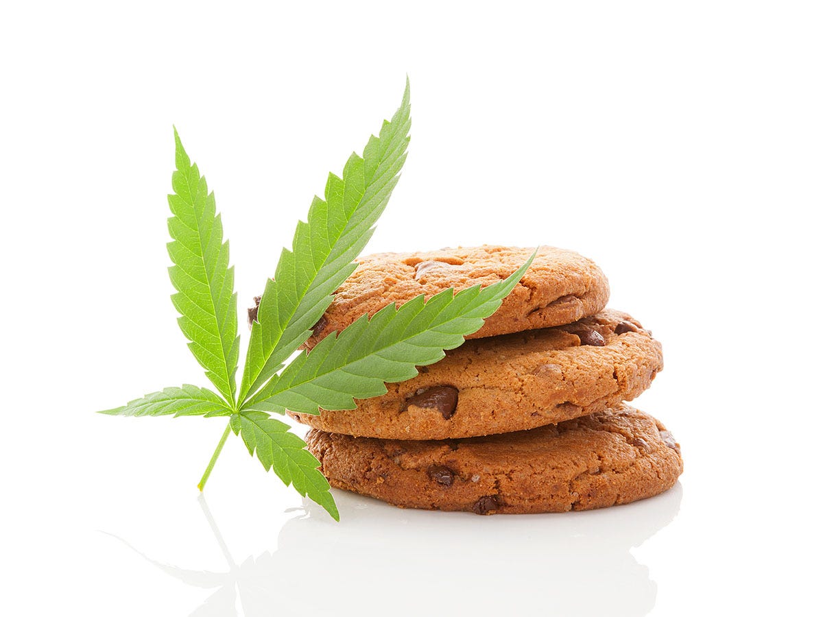 Three chocolate chip cookies stacked on top of each other with a cannabis leaf next to it