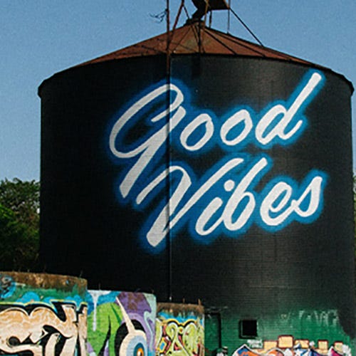 Grain silo with graffiti on it that says Good Vibes