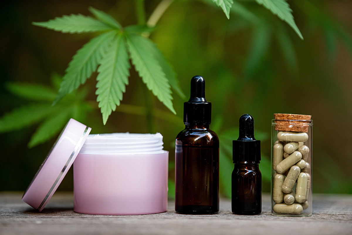 Cannabis lotion, tinctures, and capsules under a cannabis leaf