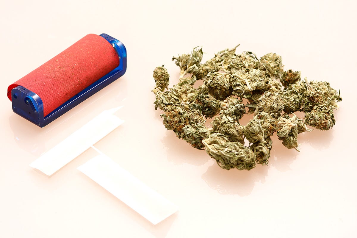 Cannabis flower, rolling papers, and a joint rolling machine