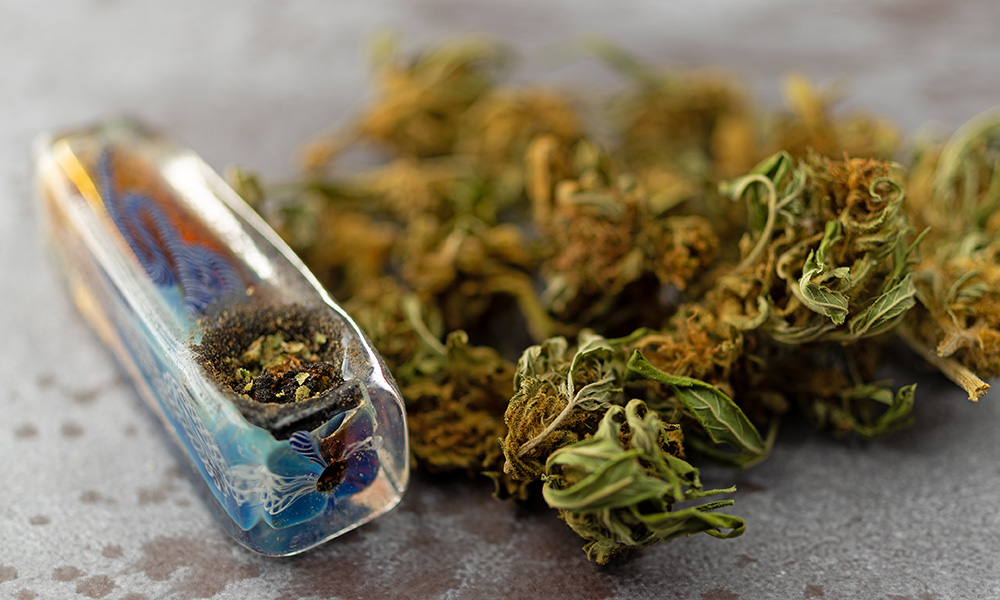 One hitter with cannabis in the bowl, next to cannabis flower