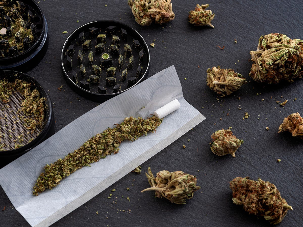 Cannabis flower in a joint next to a grinder