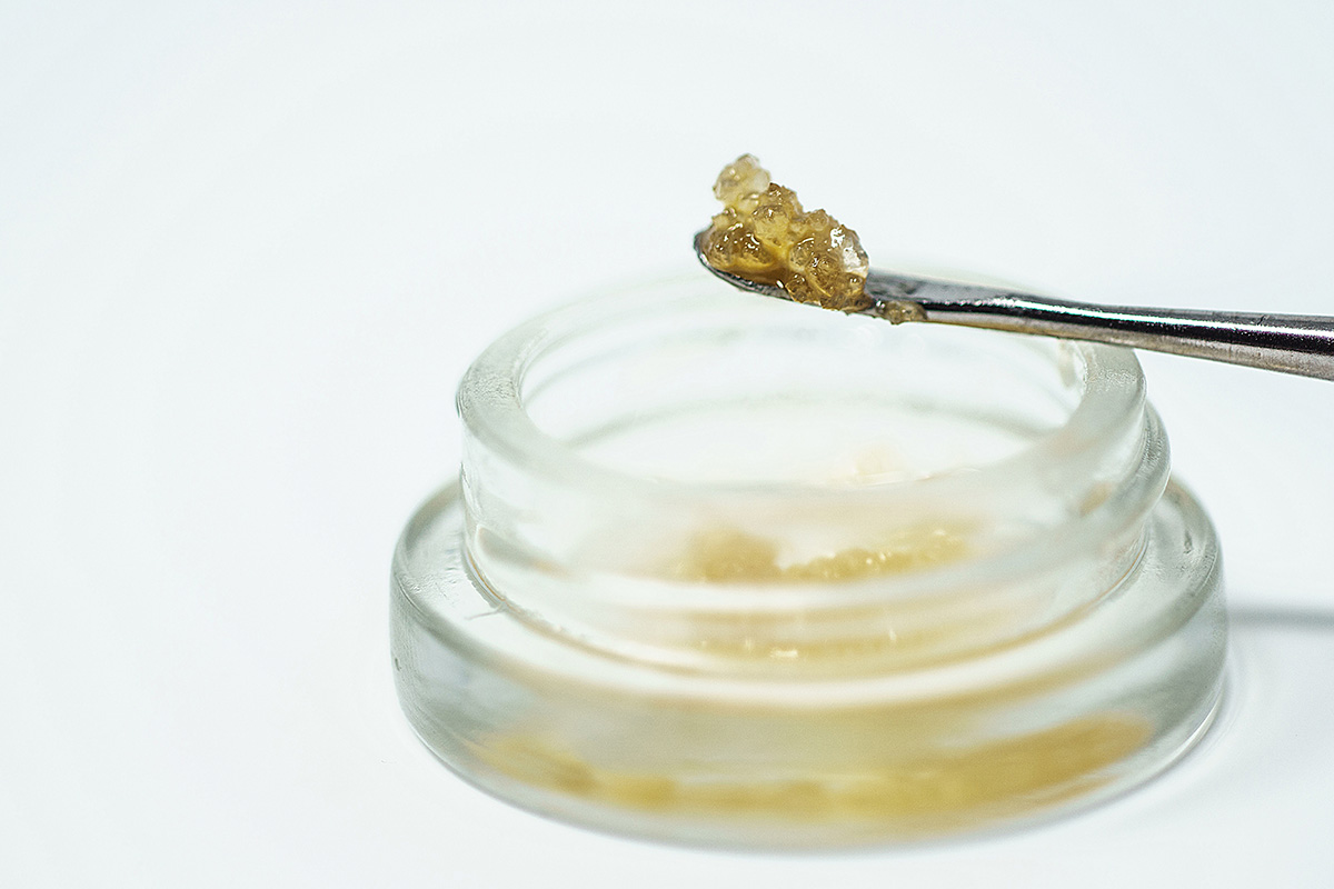 THCA diamonds in a clear jar, being scooped with a dab tool