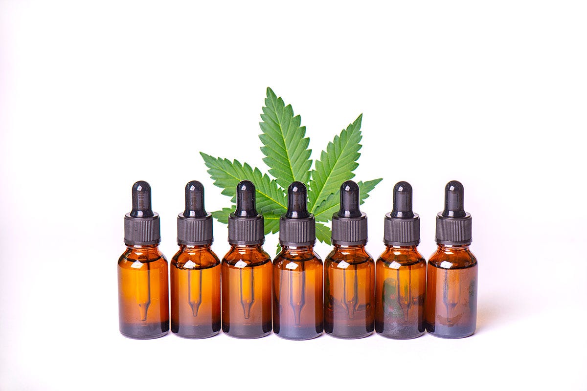 Row of tincture bottles with a cannabis leaf behind them
