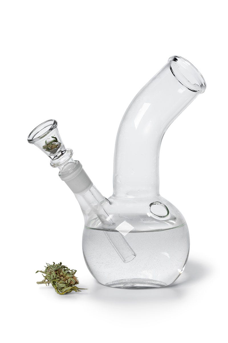 Clear glass bong with water inside and a flower bud next to it