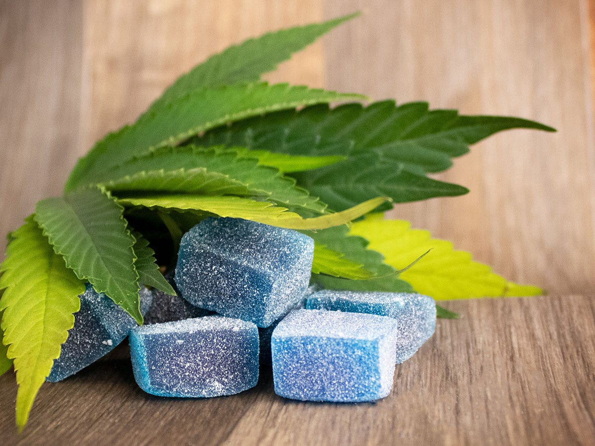 Blue CBC gummies in a pile under a cannabis leaf