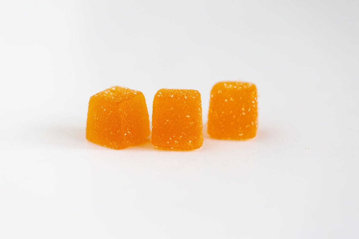 Three orange gummies on a white background