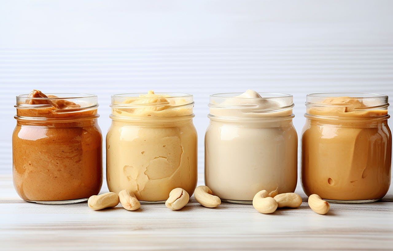 Four mason jars filled with different types of peanut butter