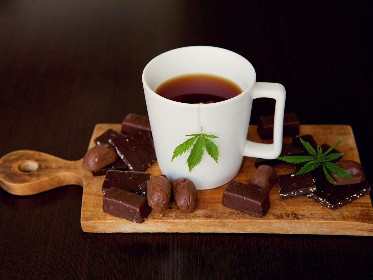 Mug of cannabis hot chocolate on a cutting board surrounded by pieces of chocolate