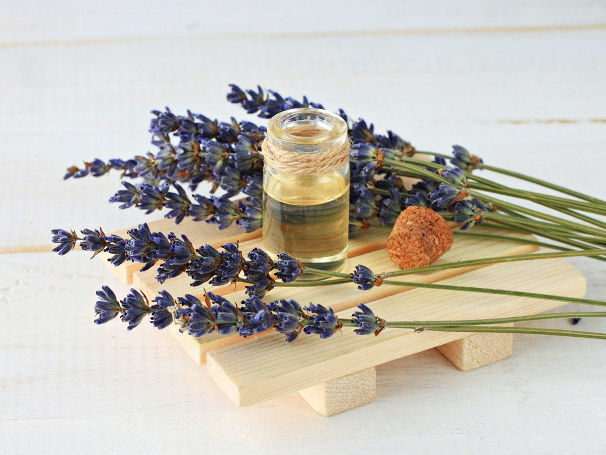 Small bottle of liquid on a cutting board surrounded by lavender stalks