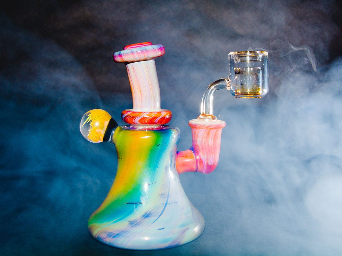 Colorful dab rig in front of a cloud of smoke