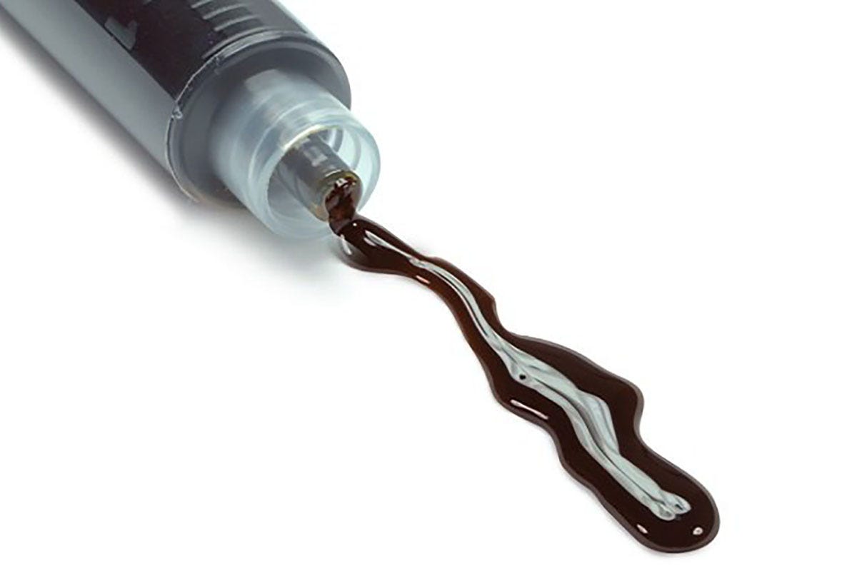 Black RSO being dispensed from a clear syringe