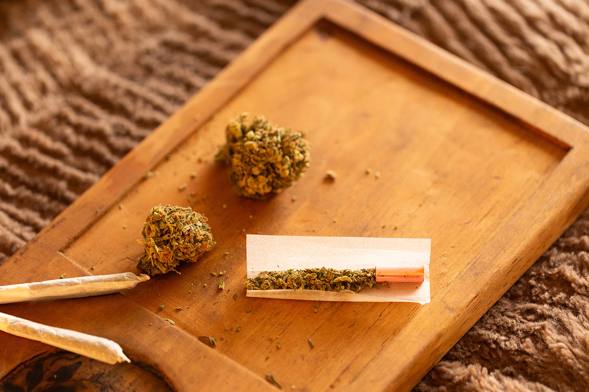 Wood rolling tray with flower and a half-rolled joint