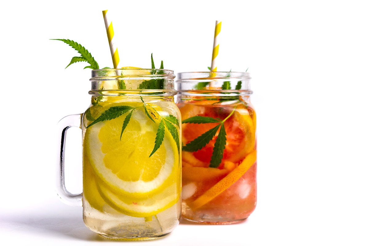 Two cannabis mocktails in clear mason jars with handles and yellow straws sticking out