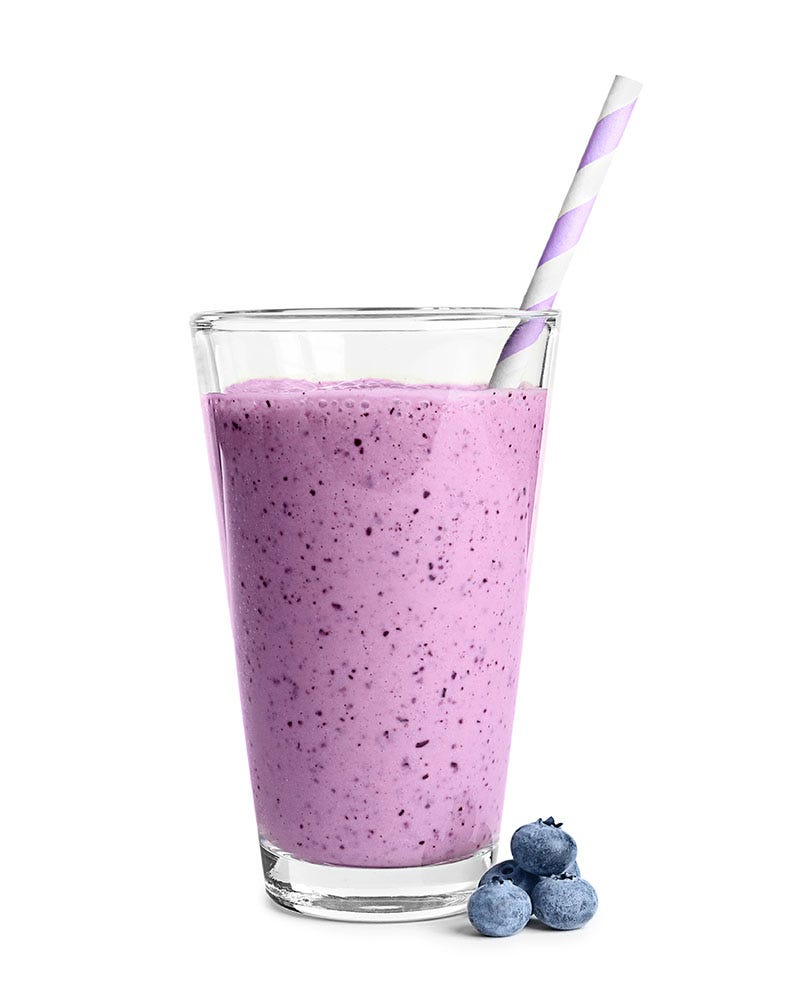 Blueberry smoothie in a tall, clear glass with a purple straw