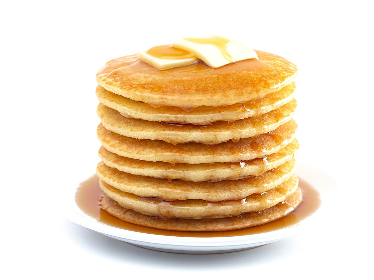 A tall stack of pancakes drips with THC syrup against a white backdrop