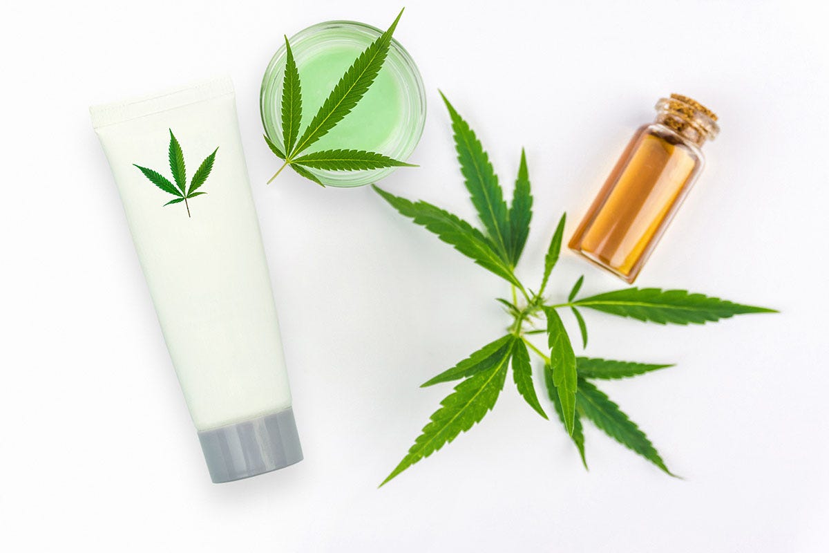 THC location, balm, and oil in cosmetic bottles surrounded by cannabis leaves
